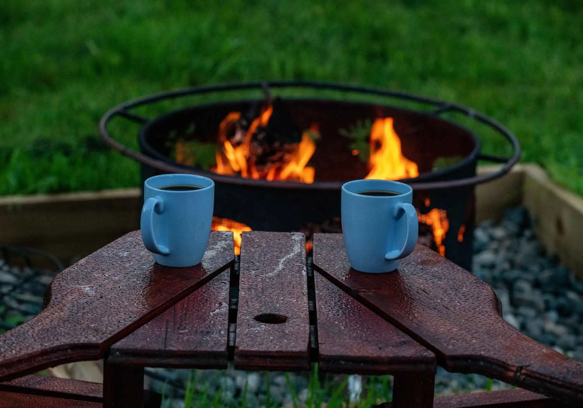 Two mugs of coffee on a table beside a morning fire at Kayanara.
