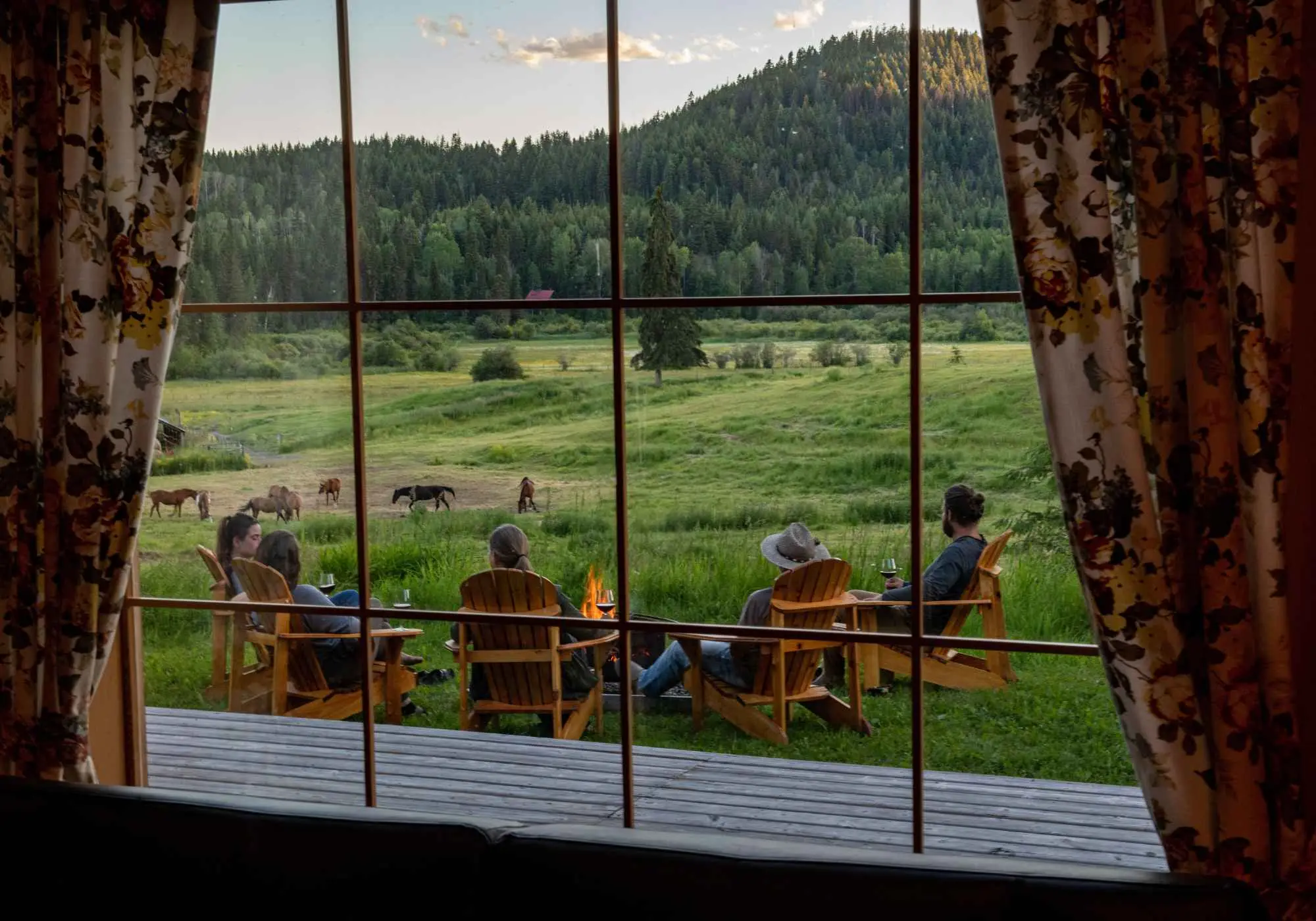 The view from inside a cabin at Kayanara, through the window to the deck, the meadow, and the horses.