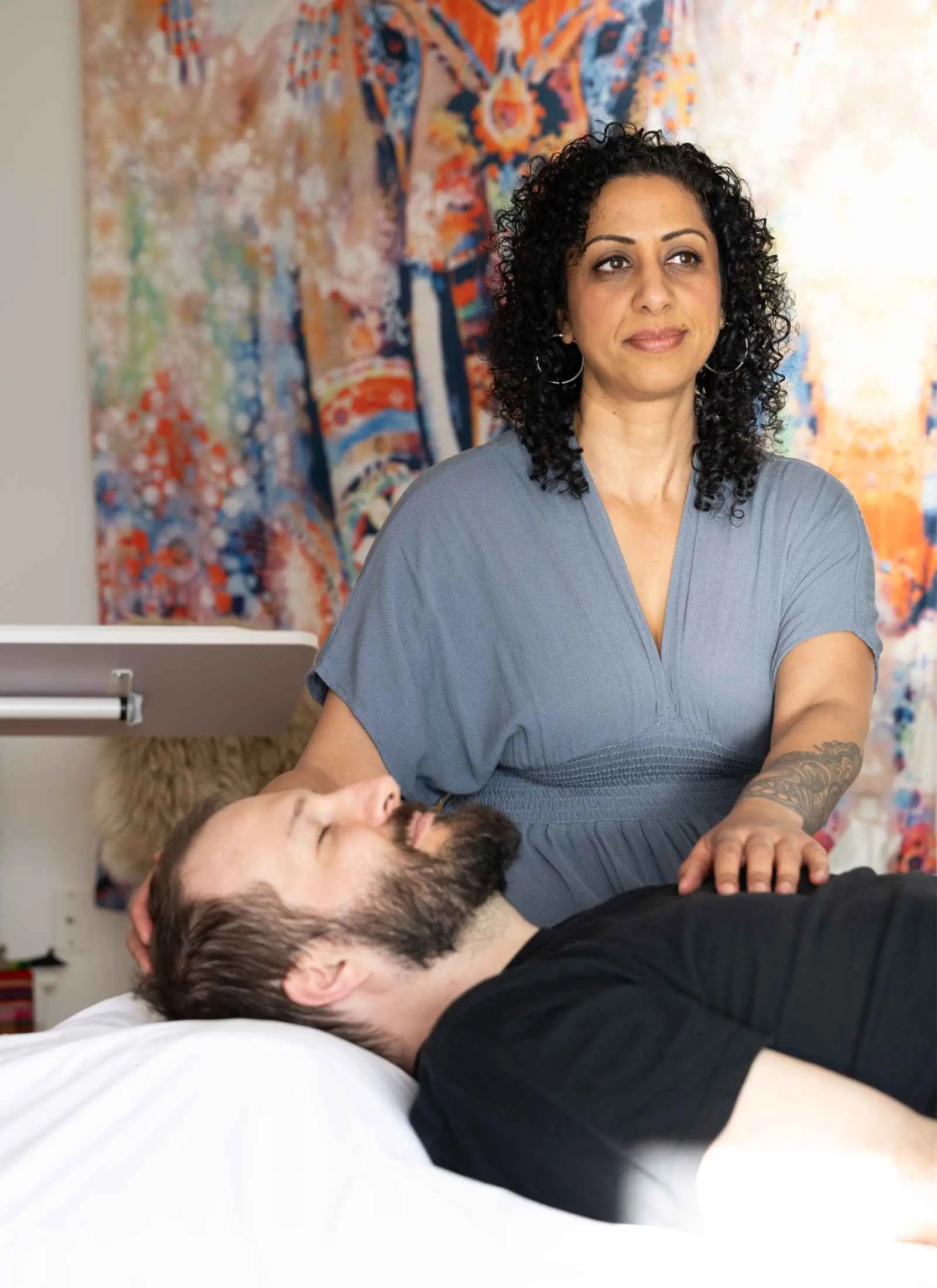 Pam Dhillon working with her hands at the head of someone resting quietly.